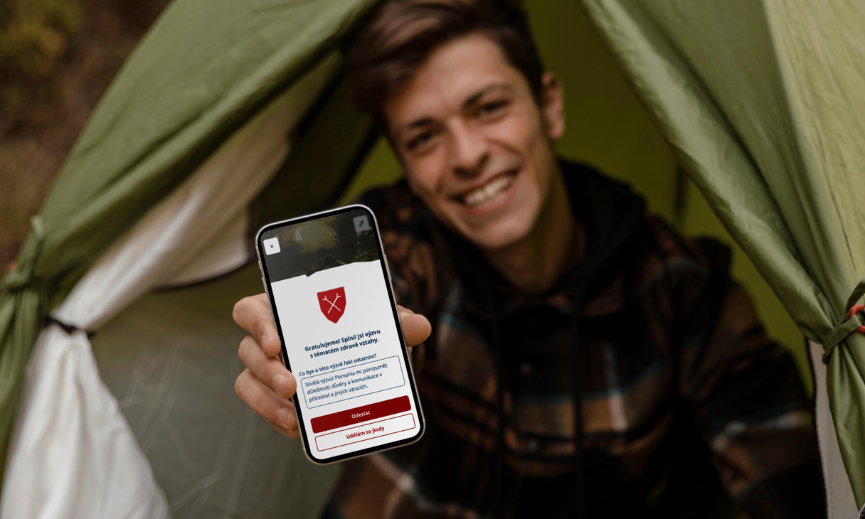Scout in tent holding mobile with challenge completion congratulation