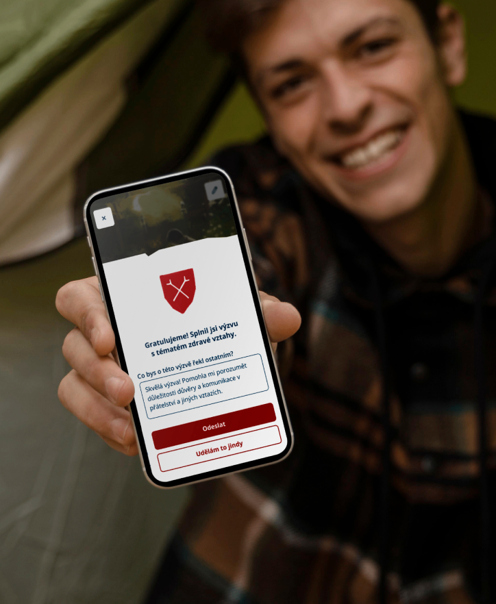 Scout in tent holding mobile with challenge completion congratulation