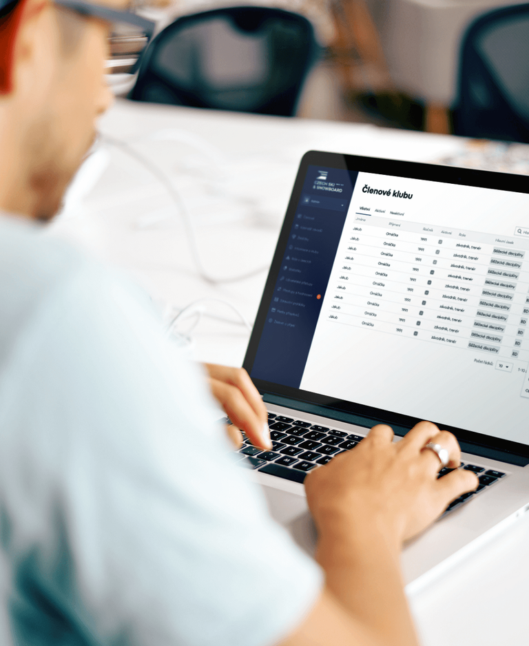 Man working on a laptop with club member list in management system